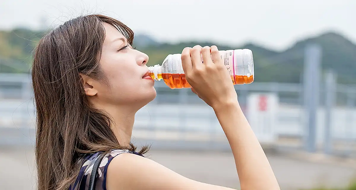 ペットボトルの麦茶を飲む女性